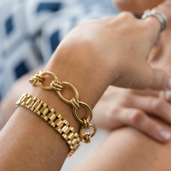 Gold chain bracelet on a wrist with a blurred background