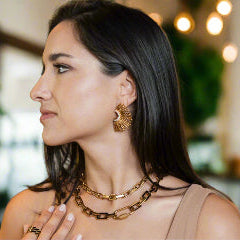 Woman wearing gold jewelry in a blurred indoor setting
