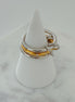 Three rings stacked on top of each other, with the top two rings in gold color and the bottom one in silver, displayed on a white stand on a marble surface.