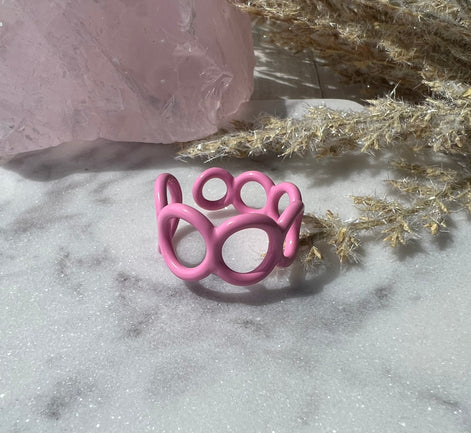 Pink colored enamel ring with small circle cut outs adjustable in size