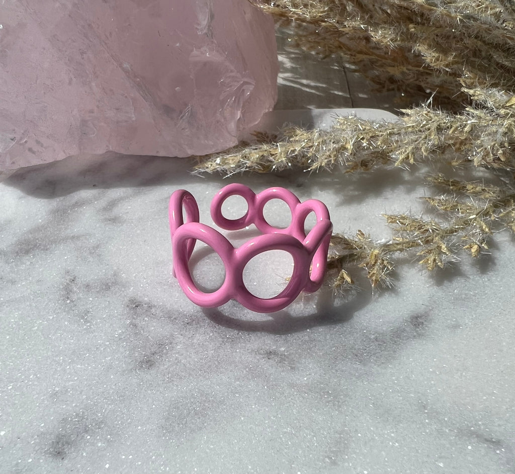 Pink colored enamel ring with small circle cut outs adjustable in size