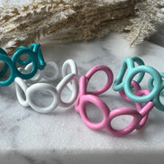 Teal, white, pink and mint green blue colored enamel rings with small circle cut outs adjustable in size