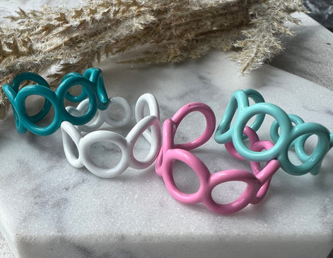 Teal, white, pink and mint green blue colored enamel rings with small circle cut outs adjustable in size