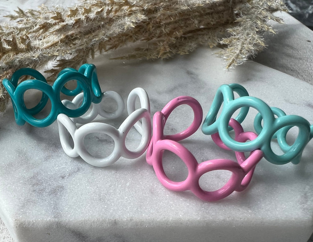 Teal, white, pink and mint green blue colored enamel rings with small circle cut outs adjustable in size